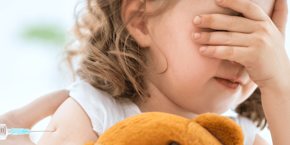 Image of a child closing her eyes before having a vaccine administered. how to administer vaccinations to infants and children. vaccinating children