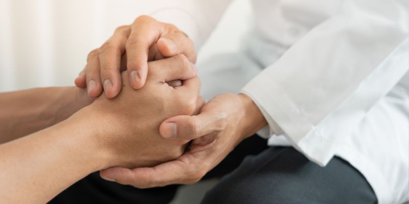 Image showing a healthcare professional holding a patient's hands, providing compassionate support amid grief and loss,