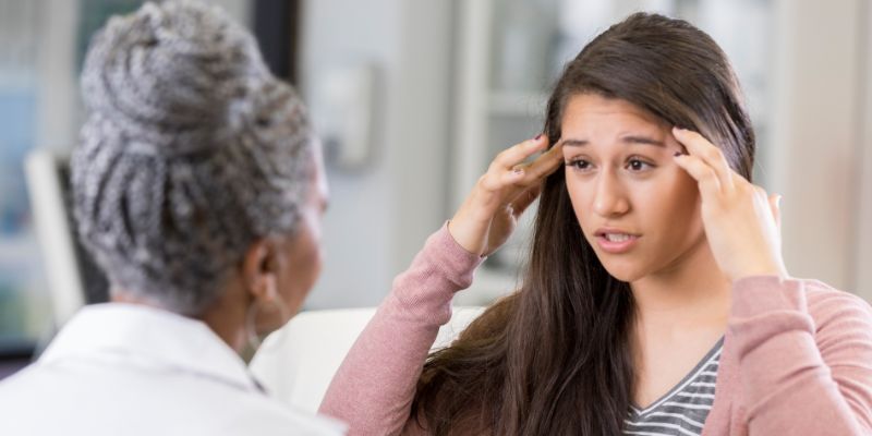 Image showing a young woman complaining of head pain to a healthcare professional
