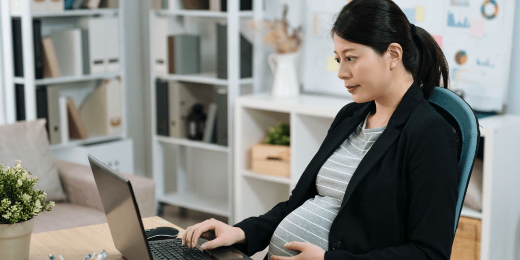 A pregnant woman sat at her work desk