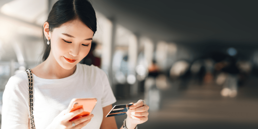 A woman holds her phone and credit card, presumably making a purchase on an online store. Consumer rights are crucial to protect customers and retailers.