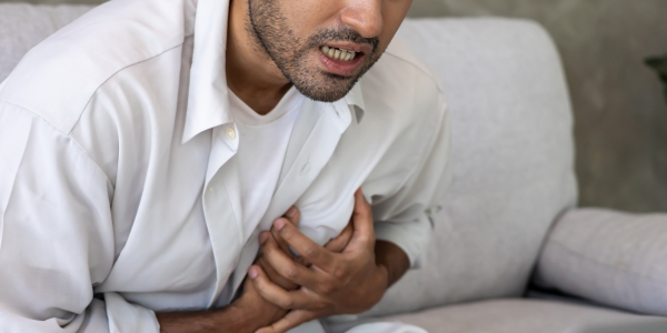 image showing man clutching check with chest pain who is having heart attach for Coronary Heart Disease Update in Primary Care course